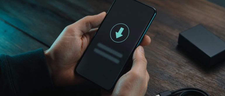 Смартфон в руке со стрелкой загрузки — установка приложения на Android